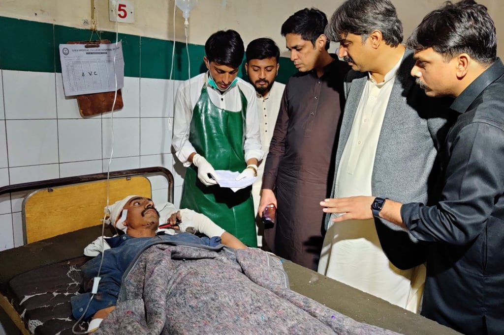 Sindh province Transport Minister Awais Qadir Shah (second right) talks with a victim of a train-bus collision in Pakistan on Friday. Photo: AFP