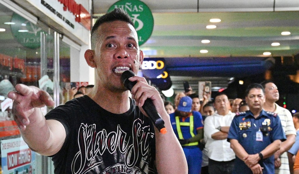 Hostage-taker Archie Paray (at left) talks to the media after releasing hostages outside a mall in Manila on Monday. Photo: AFP