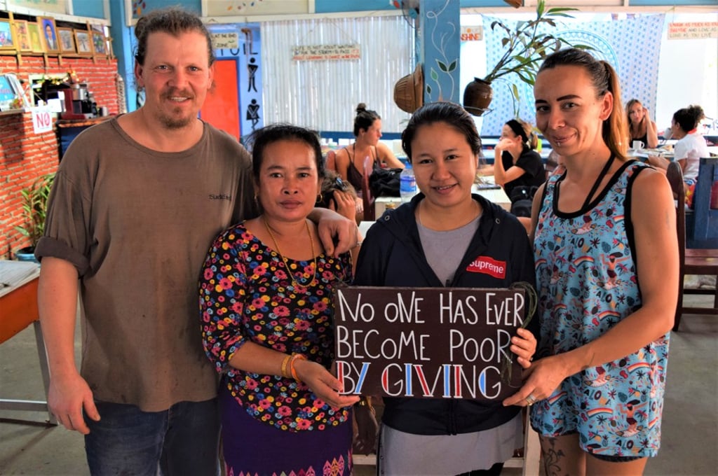 Mama Tanon (second from left) with visitors and one of many inspirational signs at her eponymous guest house in Don Det. Photo: Red Door News