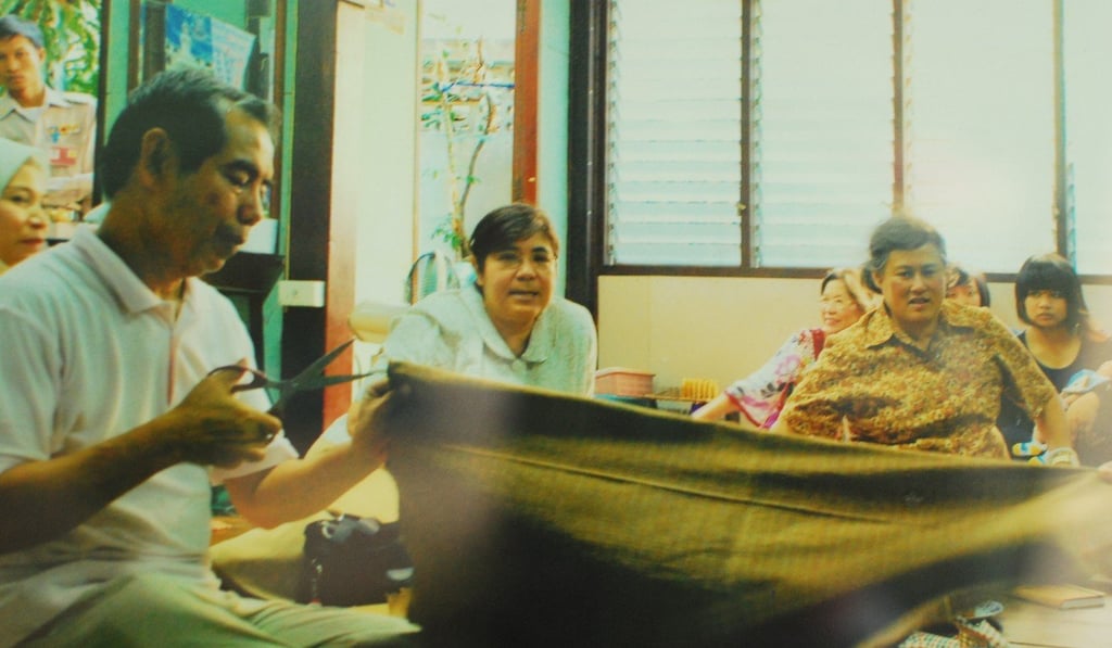 Nipon Manuthas, left, owner of Phamai Baan Krua silk brand, shows Princess Maha Chakri Sirindhorn, right (in yellow shirt), his silk products in 2010. Photo: Handout