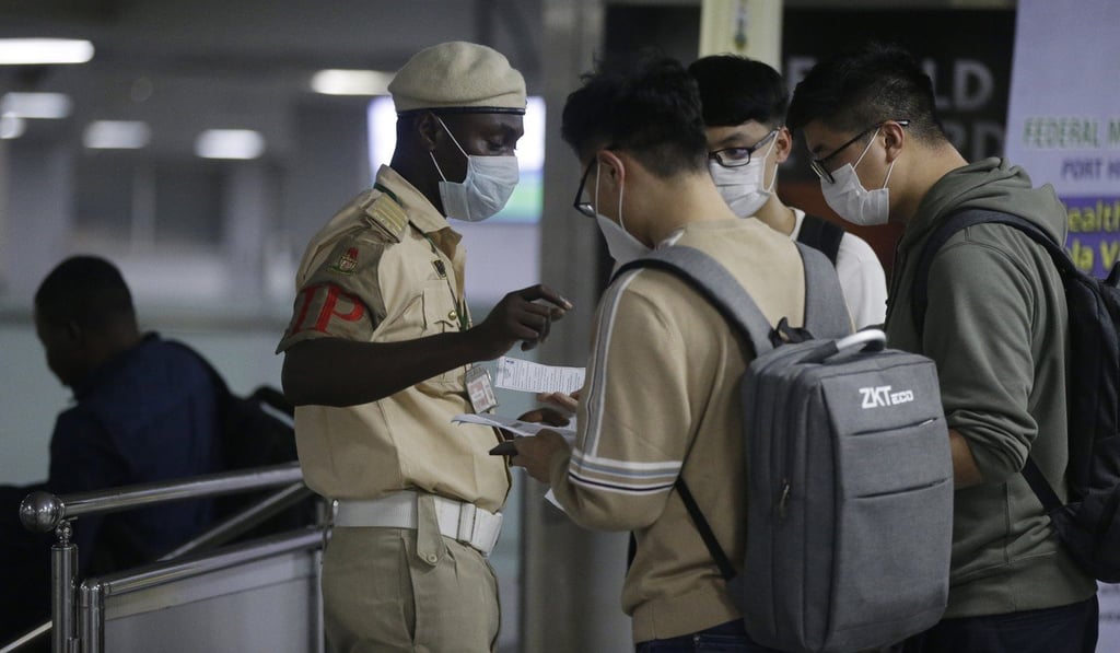 A Nigerian immigration officer speaks to Chinese nationals arriving at the Murtala Muhammed International Airport in Lagos on Wednesday. Photo: AP A Nigerian immigration officer speaks to Chinese nationals arriving at the Murtala Muhammed International Airport in Lagos on Wednesday. Photo: AP