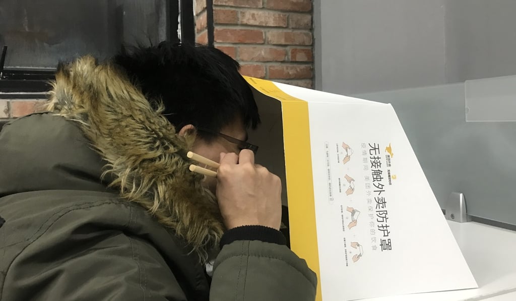 Someone eating their food inside a “contactless shield” from Meituan. Source: Handout