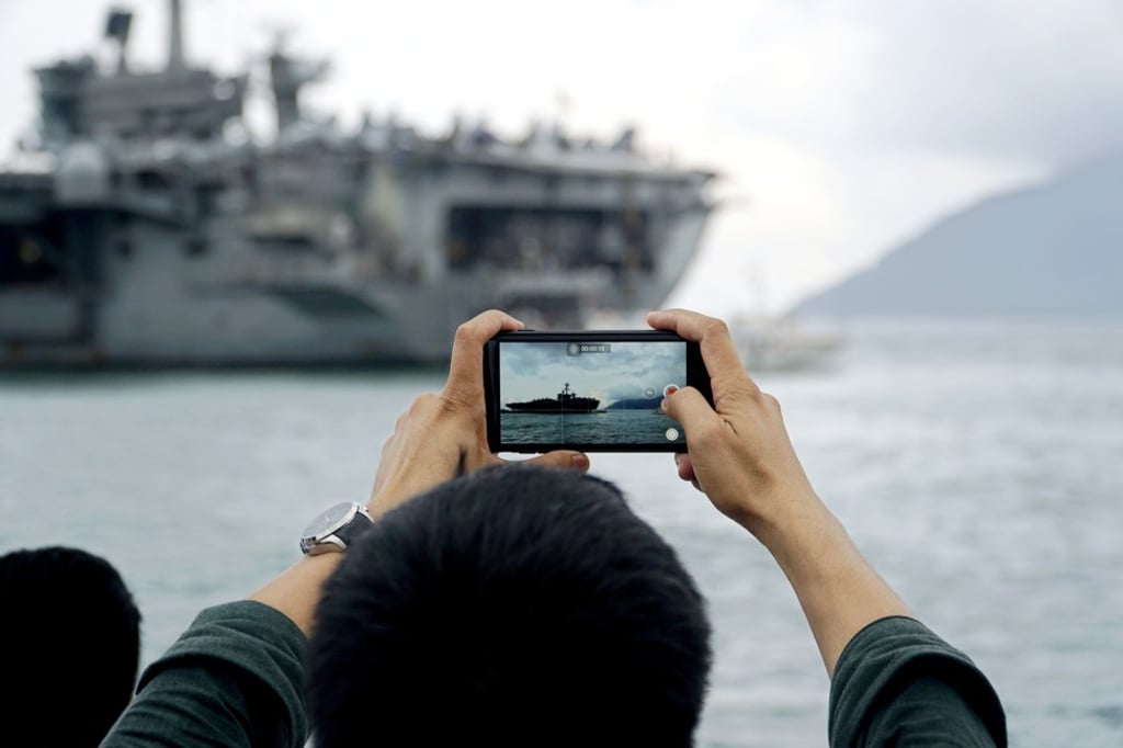 A man takes photos of the aircraft carrier USS Theodore Roosevelt at the harbour of Da Nang, Vietnam on March 5. Photo: EPA-EFE