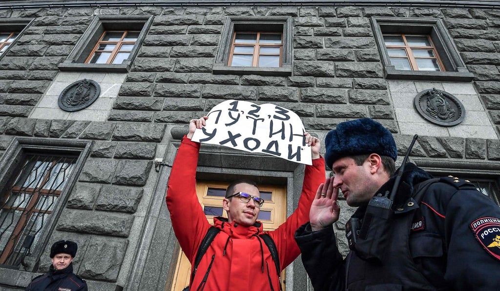 A Russian police officer speaks with a protester as he holds a sign reading “Putin – resign” during an unsanctioned rally in front of the headquarters of the FSB security services in central Moscow. Photo: AFP