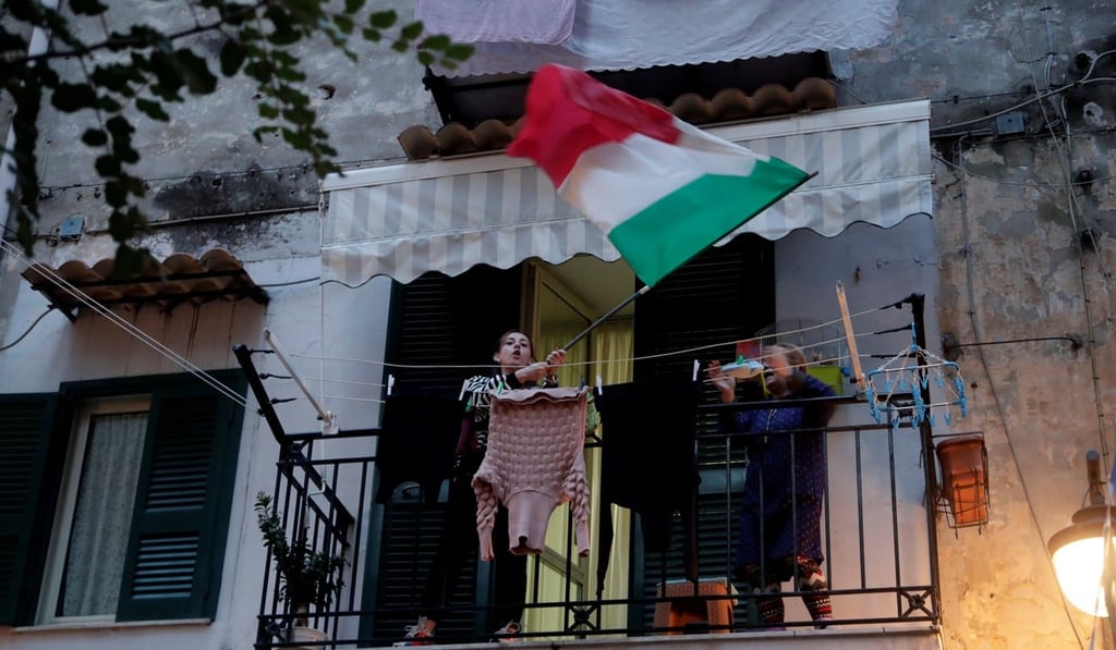 A woman waves an Italian flag in Naples, Italy, amid a coronavirus lockdown. Photo: Reuters