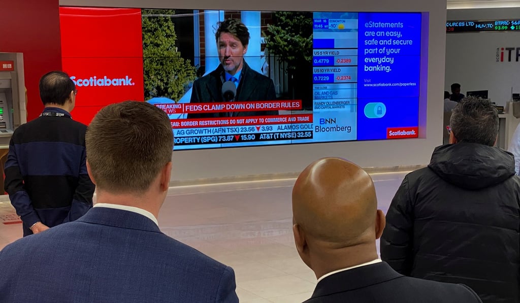 At a bank in Toronto on Monday, people watch Canadian Prime Minister Justin Trudeau’s announcement of measures to combat the spread of coronavirus. Photo: Reuters At a bank in Toronto on Monday, people watch Canadian Prime Minister Justin Trudeau’s announcement of measures to combat the spread of coronavirus. Photo: Reuters
