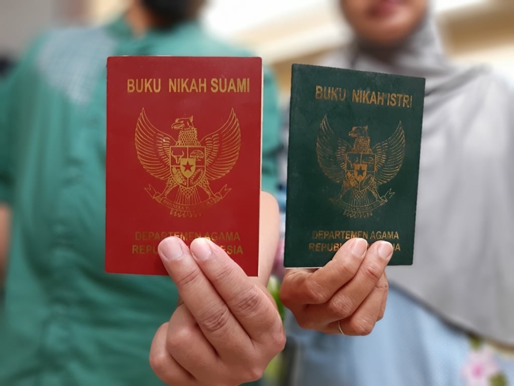A Muslim couple hold up their marriage certificates in Jakarta. The red one is for the husband, while the green is his wife’s. Photo: Ade Mardiyati