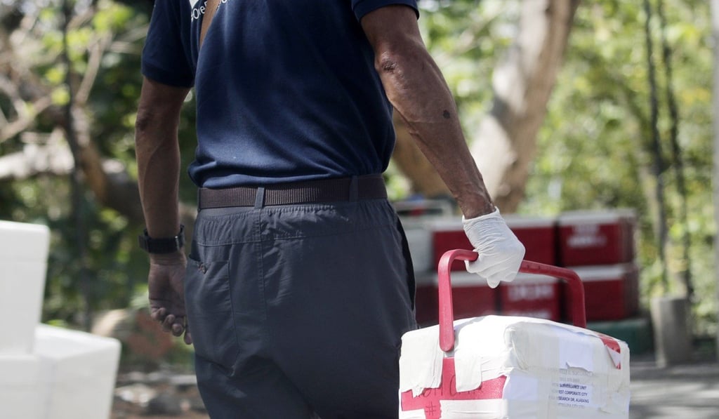 A health worker carries a sealed box containing Covid-19 specimen in Muntinlupa city, south of Manila, on March 13. Photo: EPA