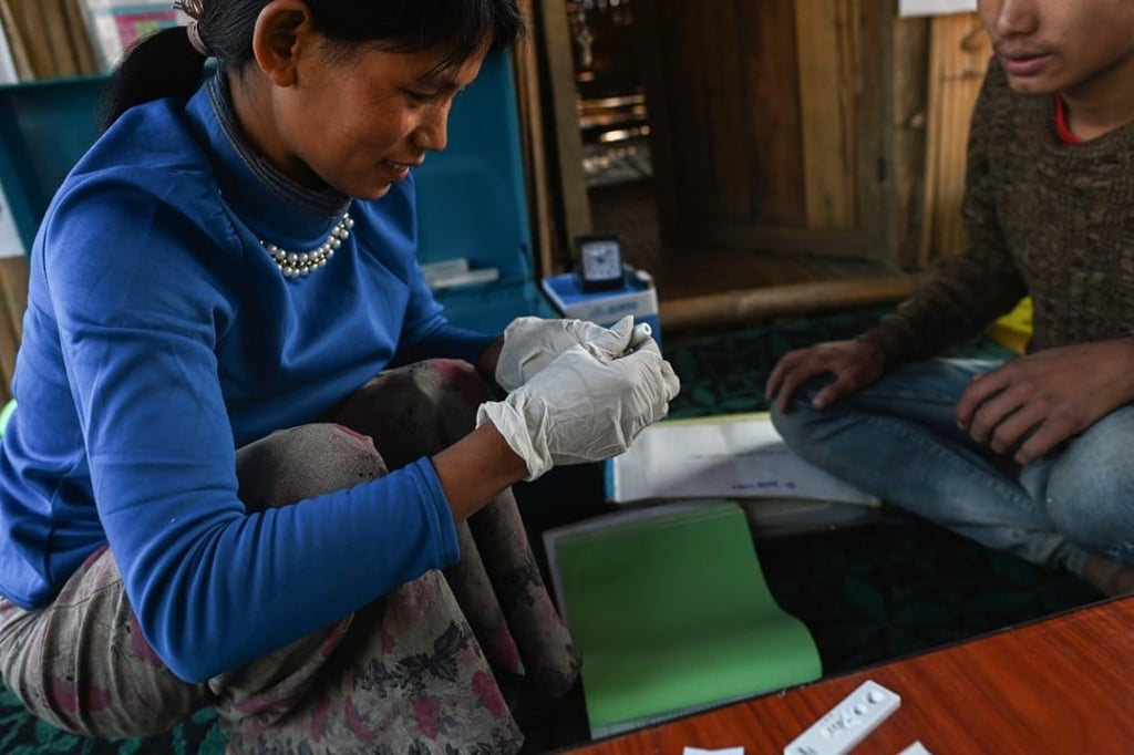 Htan Pi takes a blood sample from a patient to test for malaria. She insists she is not in competition with her mother – the village shaman. Photo: AFP