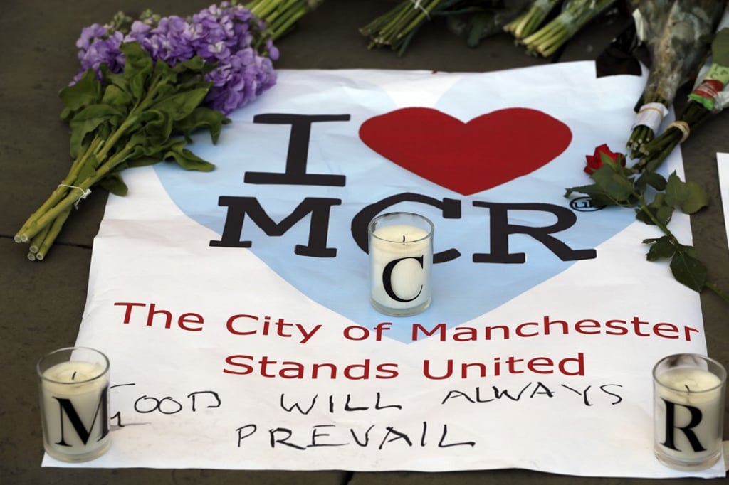 A sign is seen with flowers and candles after a vigil in Albert Square, Manchester, England, in May 2017. Photo: AP A sign is seen with flowers and candles after a vigil in Albert Square, Manchester, England, in May 2017. Photo: AP