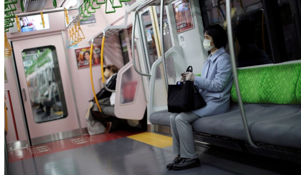 A woman, wearing a protective mask, rides on an almost empty train in Japan. Photo: Reuters