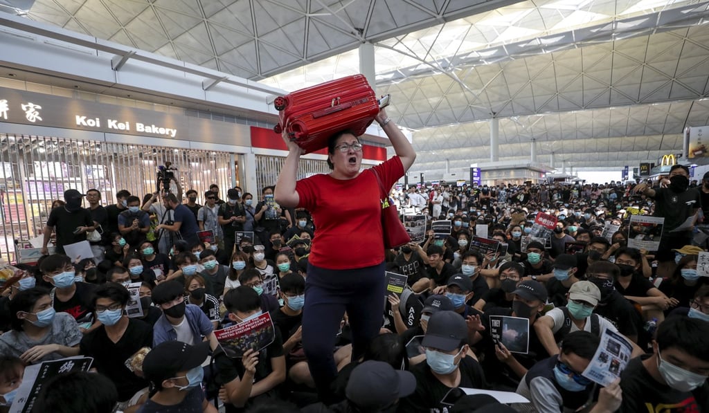 A traveller wades through anti-government protesters at Hong Kong International Airport’s arrivals hall on August 13, 2019. Photo: Sam Tsang