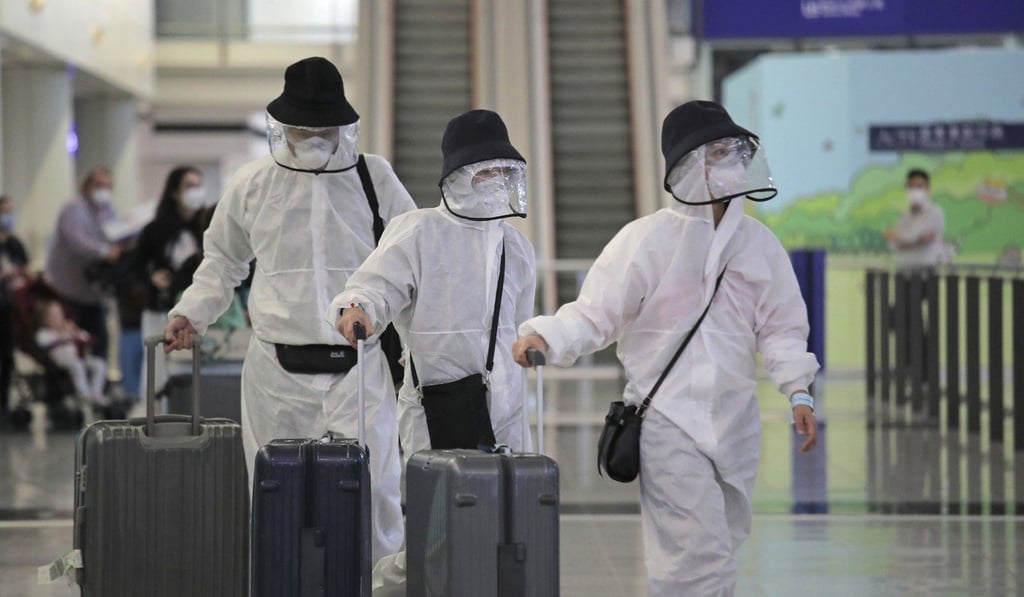 Passengers wear protective suits and face masks as they arrive at Hong Kong airport. Photo: AP Passengers wear protective suits and face masks as they arrive at Hong Kong airport. Photo: AP