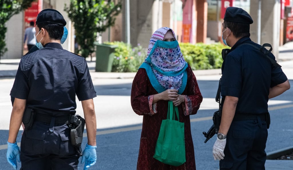 A member of the Royal Malaysia Police speaks to a woman during a movement control order to limit the activities of people to curb the spread of the coronavirus. Photo: AFP