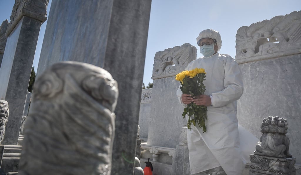 A staff member offers chrysanthemums on behalf of relatives at a grave in the Babaoshan Cemetery in Beijing. Photo: Xinhua