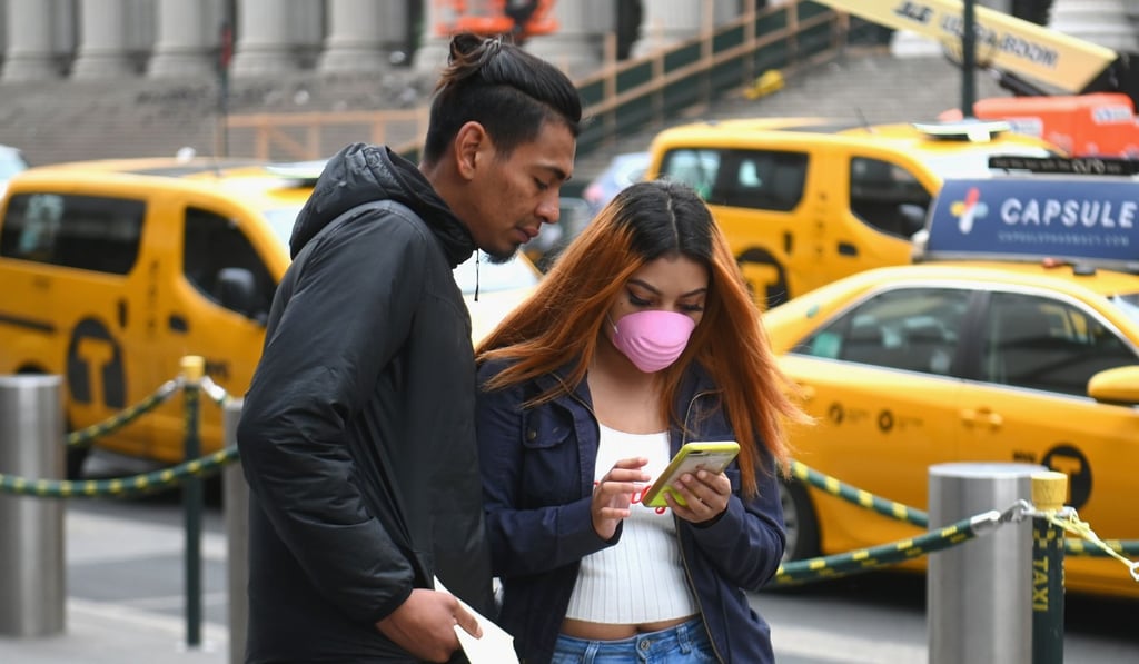 A woman looks at her phone wearing a face mask in New York City. Photo: AFP A woman looks at her phone wearing a face mask in New York City. Photo: AFP
