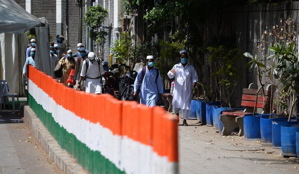 Men wearing protective face masks walk to a special service bus taking them to a quarantine facility in New Delhi. Photo: AFP