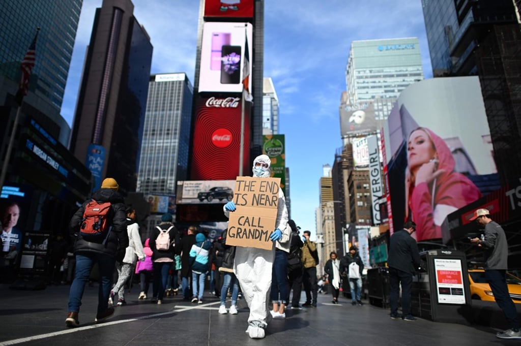 A man wearing a hazmat suit and a mask holds a humorous sign at Times Square in New York on March 14. The city has fast become the epicentre of the US’ coronavirus outbreak. Photo: AFP