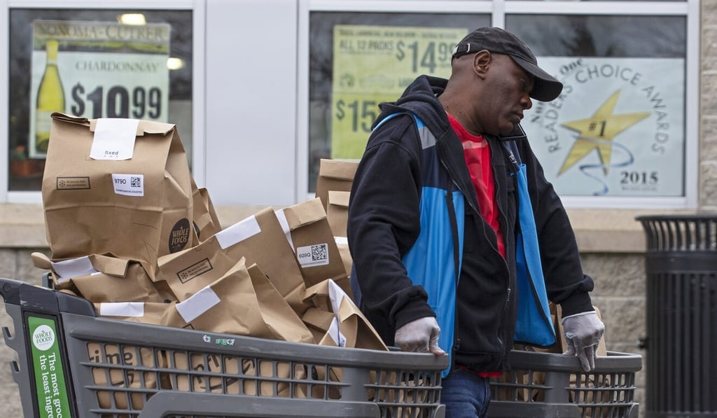 An Amazon Prime delivery worker pushes carts of online grocery purchases outside a Whole Foods market in Cambridge, Massachusetts on Monday. Photo: EPA-EFE An Amazon Prime delivery worker pushes carts of online grocery purchases outside a Whole Foods market in Cambridge, Massachusetts on Monday. Photo: EPA-EFE