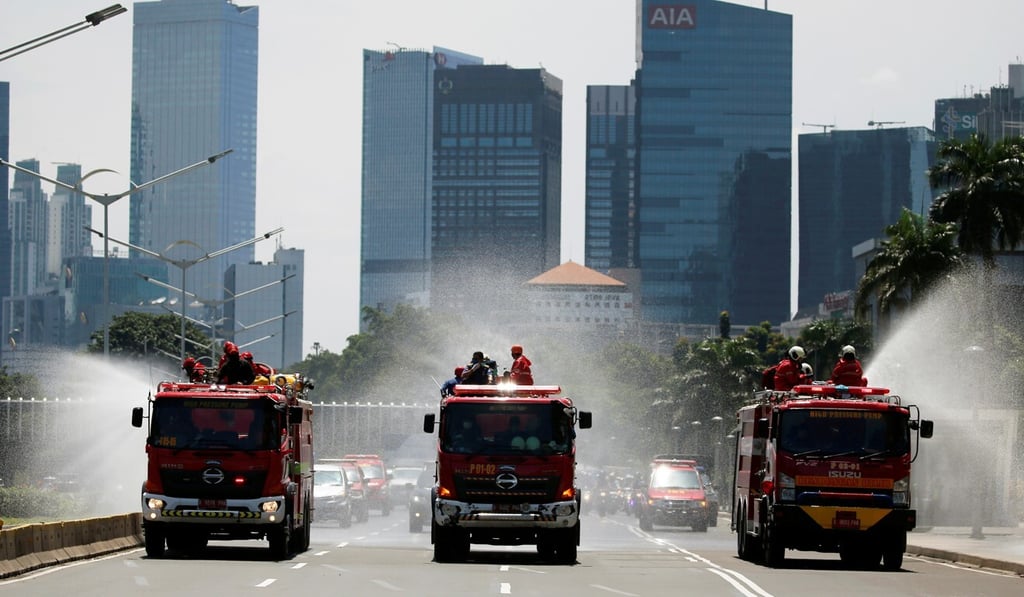 Firefighters spray disinfectant using high pressure pump trucks on a main road in Indonesia’s capital of Jakarta on Tuesday. Photo: Reuters