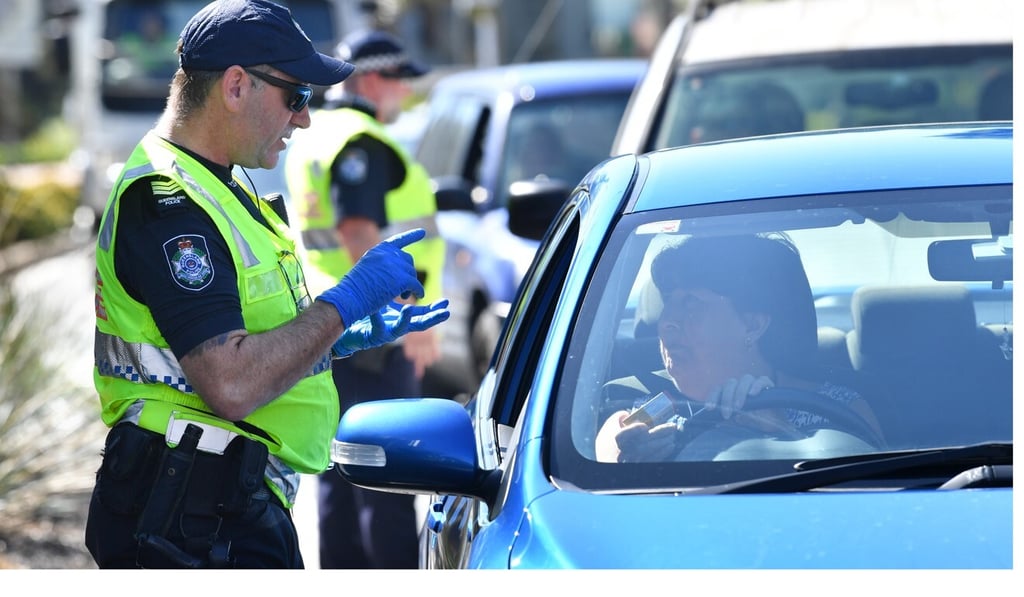 Police officers stop cars at a checkpoint on the Queensland and New South Wales border, after it closed in an attempt to curb the spread of coronavirus. Photo: EPA-EFE