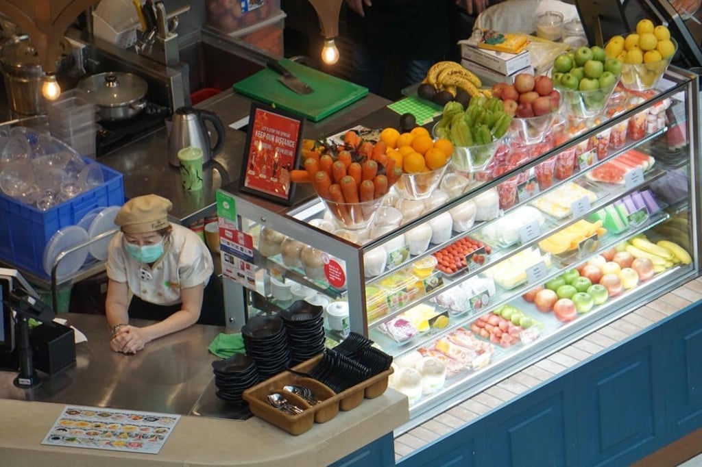 An employee wearing a face mask waits for customers at a fruit stall in a Singapore food court. Photo: AFP An employee wearing a face mask waits for customers at a fruit stall in a Singapore food court. Photo: AFP