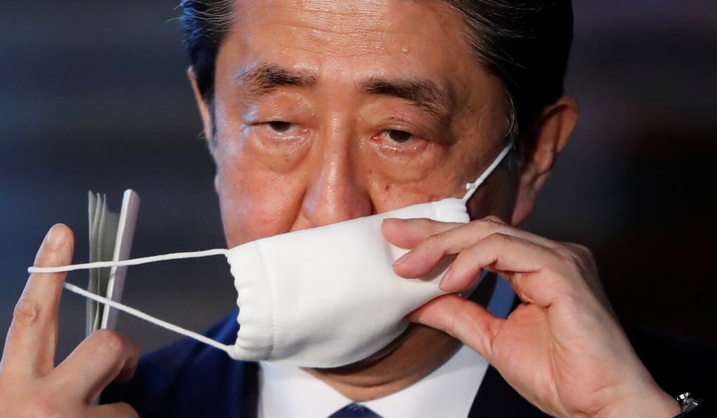 Japan's Prime Minister Shinzo Abe takes off his face mask as he arrives to speak to the media. Photo: Reuters
