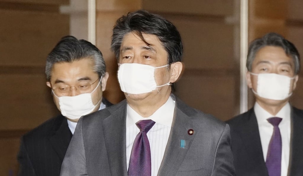 Japanese Prime Minister Shinzo Abe, centre, wears a reusable cloth face mask as he leaves his office in Tokyo on Sunday. Photo: Kyodo