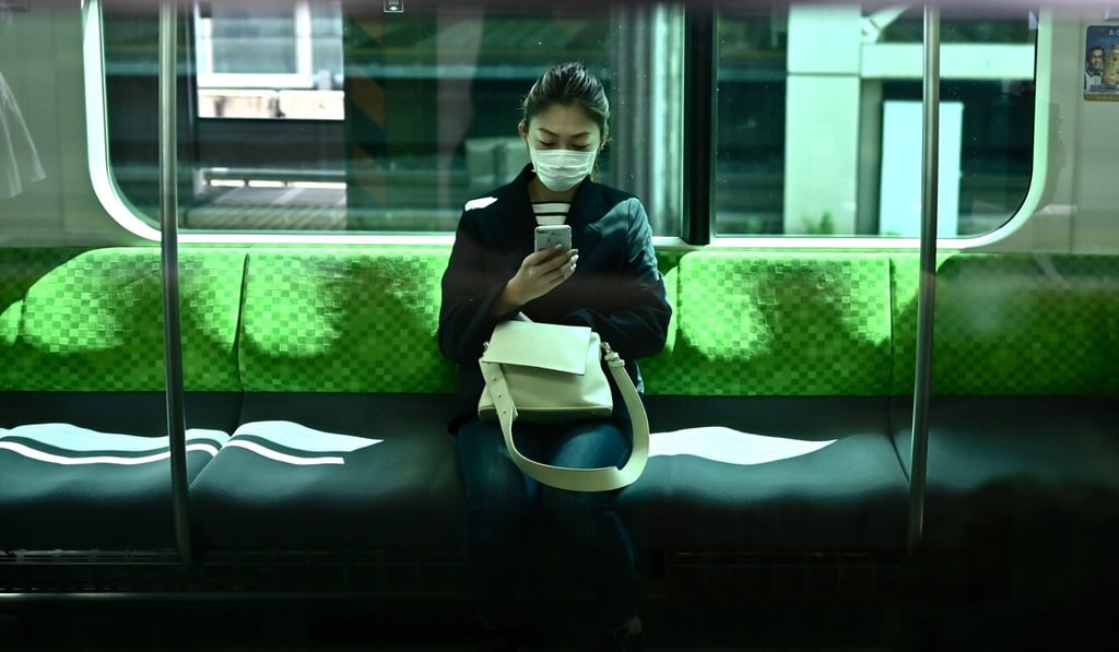 A woman uses her phone on a train in Tokyo on Wednesday, the first day of the state of emergency. Photo: AFP A woman uses her phone on a train in Tokyo on Wednesday, the first day of the state of emergency. Photo: AFP