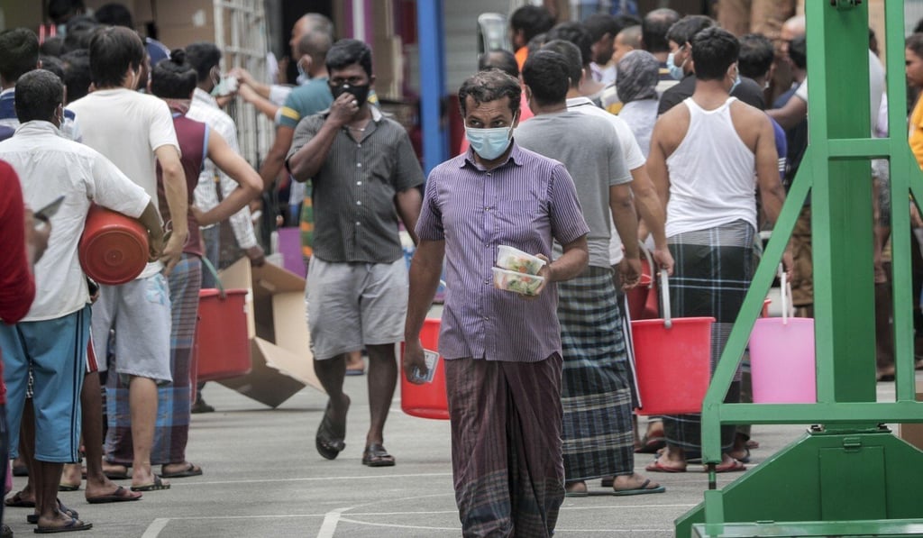 A foreign worker wearing a surgical mask collects food at one of the dormitories in Singapore that were locked down on Sunday. Photo: EPA A foreign worker wearing a surgical mask collects food at one of the dormitories in Singapore that were locked down on Sunday. Photo: EPA