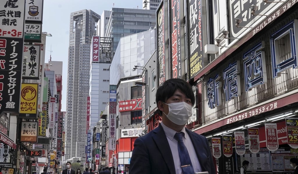 A businessman wearing a protective mask walks in Tokyo’s Shinjuku district. Photo: EPA