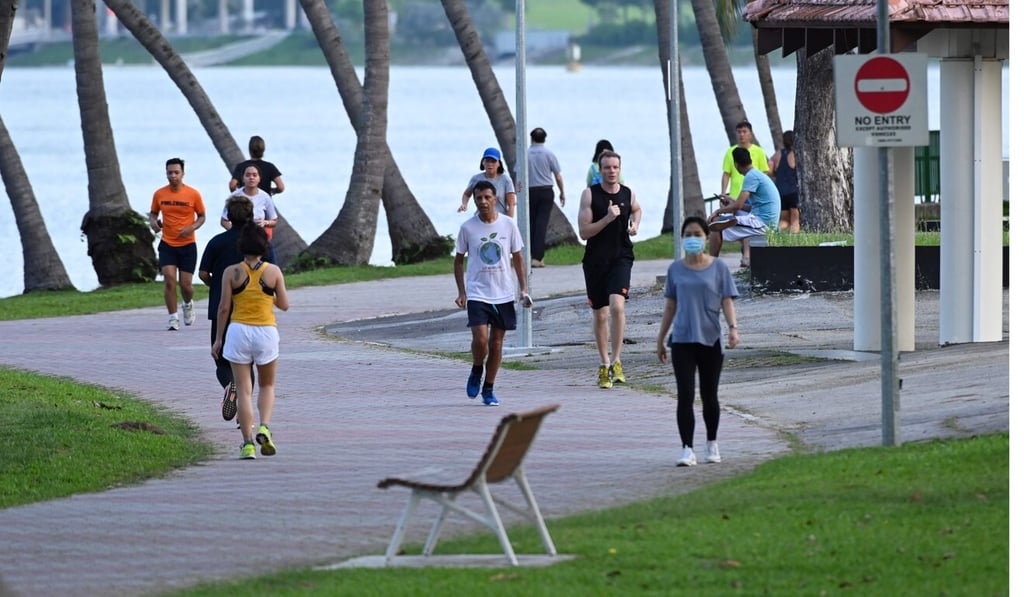 People observe social distance as preventive measure against Covid-19 as they walk and jog along the Kallang Riverside Park in Singapore. Photo: AFP People observe social distance as preventive measure against Covid-19 as they walk and jog along the Kallang Riverside Park in Singapore. Photo: AFP