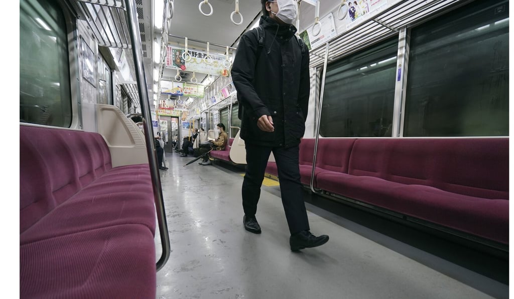 A passenger wearing a protective face mask walks on an empty train car in Tokyo, as the government set a target for a reduction in the number of commuters. Photo: AP A passenger wearing a protective face mask walks on an empty train car in Tokyo, as the government set a target for a reduction in the number of commuters. Photo: AP