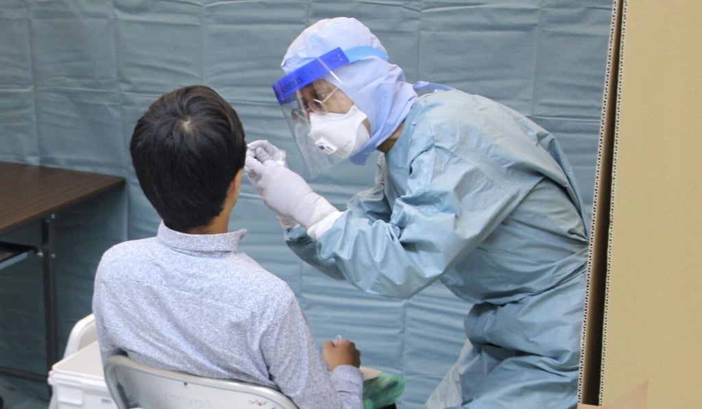 A quarantine official collects a sample for coronavirus testing from an arriving passenger at Narita airport earlier this month. Photo: Kyodo A quarantine official collects a sample for coronavirus testing from an arriving passenger at Narita airport earlier this month. Photo: Kyodo