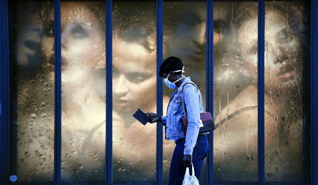 A woman wearing a face mask walks past a store window in Paris on Tuesday. Photo: AFP A woman wearing a face mask walks past a store window in Paris on Tuesday. Photo: AFP