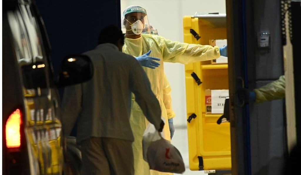 Medical staff wearing protective equipment transfer Covid-19 patients to a temporary hospital in Singapore. Photo: AFP Medical staff wearing protective equipment transfer Covid-19 patients to a temporary hospital in Singapore. Photo: AFP
