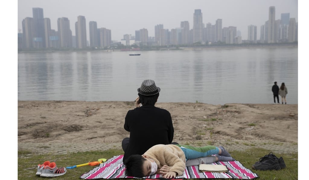 A family sit on the banks of the Yangtze River in Wuhan in central China's Hubei province, which was the epicentre of the coronavirus outbreak. Photo: AP