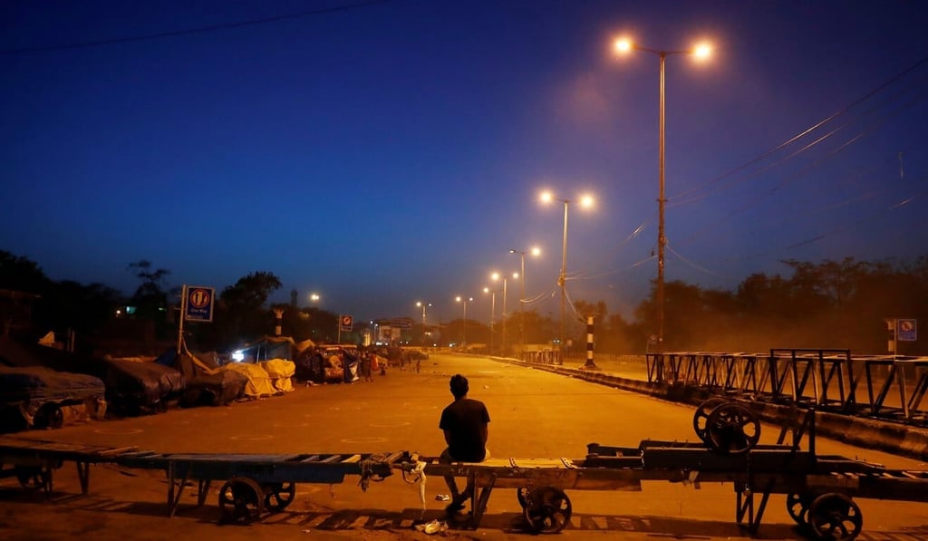 A man sits on a handcart that is serving to block a road during an extended nationwide lockdown India. Photo: Reuters