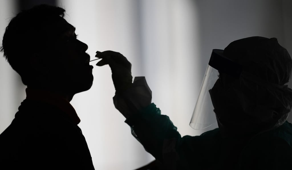 A health worker uses a swab to collect a sample for coronavirus testing from a man in Gombak on the outskirts of Kuala Lumpur. Photo: AFP