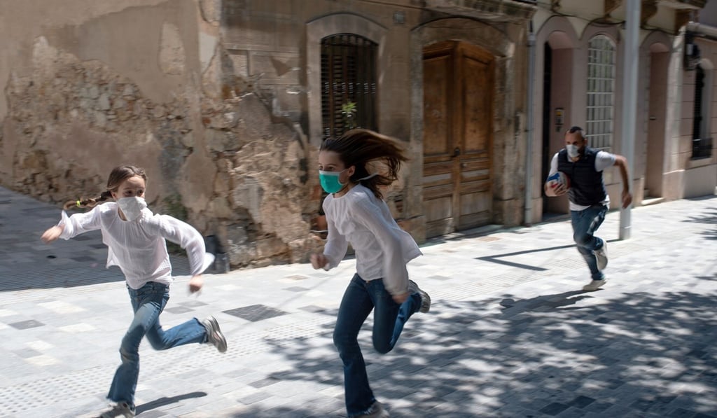 A man plays with his daughters in a Barcelona street. Photo: AFP