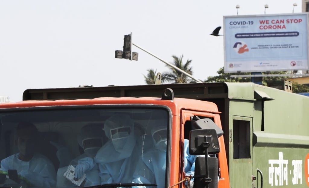 Civic workers sit inside a garbage truck carrying waste material from quarantine centres and hospitals treating Covid-19 patients in Mumbai. Photo: AP