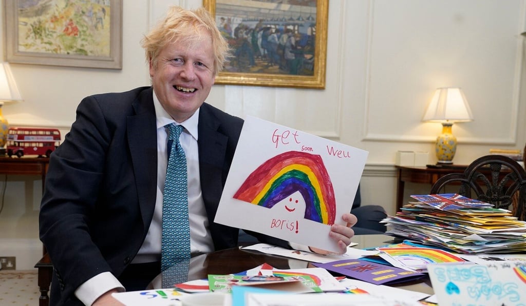 Boris Johnson is seen displaying his Get Well Soon cards sent in by children. Photo: AFP