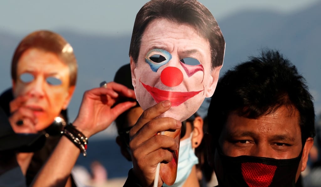 A man holds a mask depicting Italian Prime Minister Giuseppe Conte at a protest in Naples on Monday. Photo: Reuters