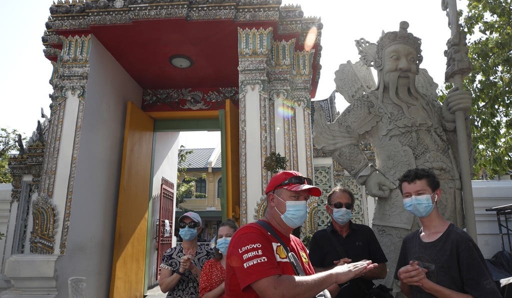 Tourists wearing face masks sanitise their hands at Wat Pho temple in Bangkok, Thailand. Photo: EPA
