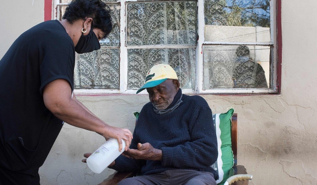 Fredie Blom is given hand sanitiser by one of his wife's daughters. Photo: AFP