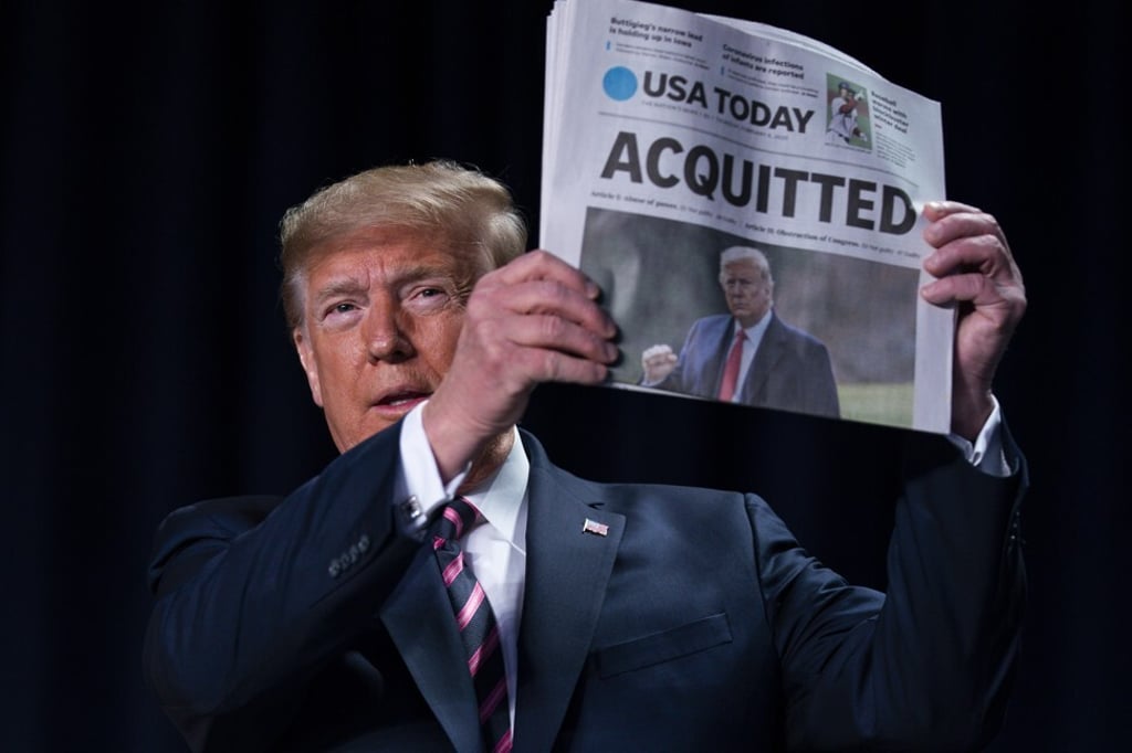 US President Donald Trump holds up a newspaper with the headline that reads “ACQUITTED” at the 68th annual National Prayer Breakfast, at the Washington Hilton, Thursday, Feb. 6, 2020, in Washington. Photo: AP