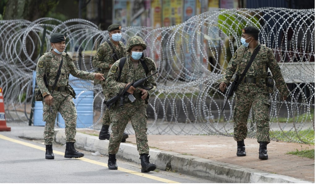 Soldiers patrol next to a locked down part of Petaling Jaya, Malaysia. Photo: AP Soldiers patrol next to a locked down part of Petaling Jaya, Malaysia. Photo: AP