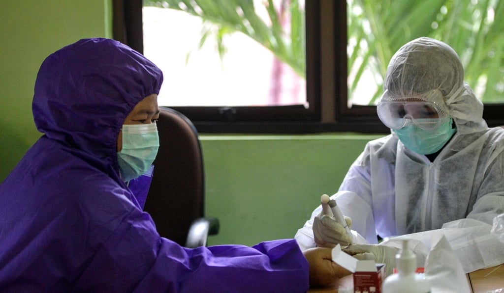 A medical worker takes a sample for a coronavirus test at a community health centre in Banda Aceh. Photo: AFP