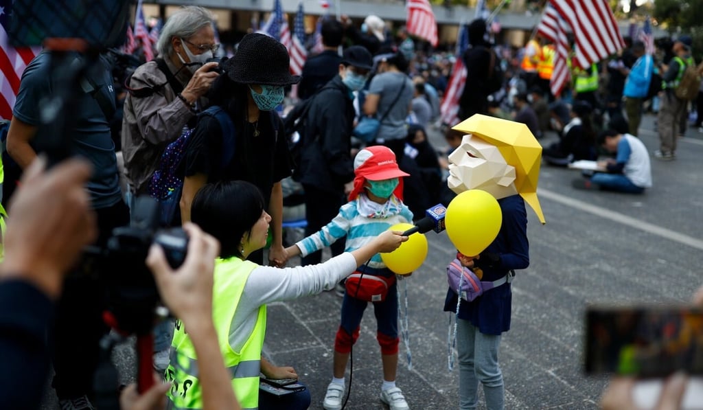 A child wearing a paper mask depicting US President Donald Trump is interviewed by a journalist during a rally in Central on December 1, 2019, to thank the US for supporting the protest movement. Photo: Reuters