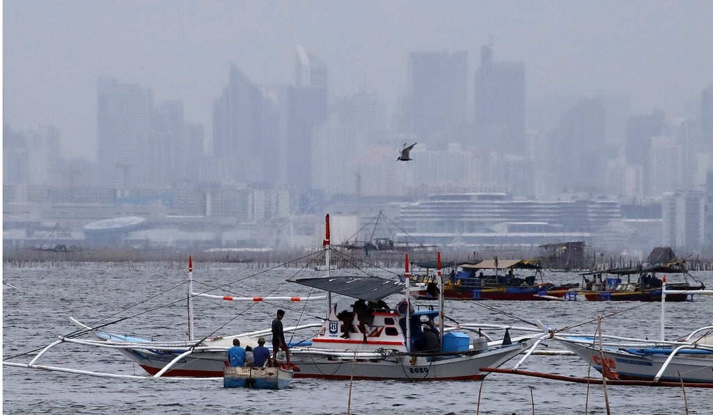 Dark clouds cover the Manila skyline as Filipino fishermen secure their boats in anticipation of an approaching typhoon. Photo: EPA-EFE